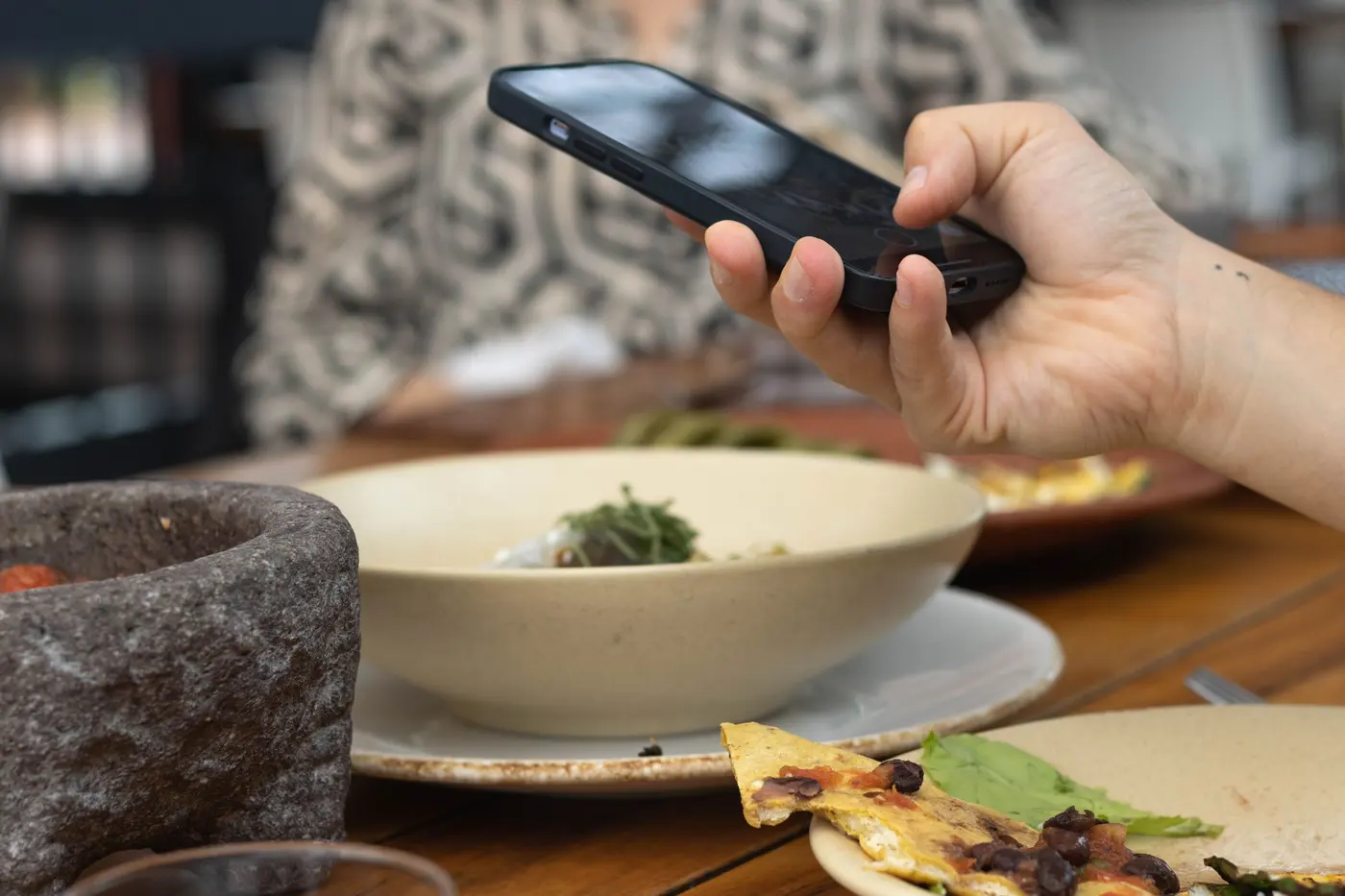 Restoran masasında telefonla QR menü açan misafirin eli